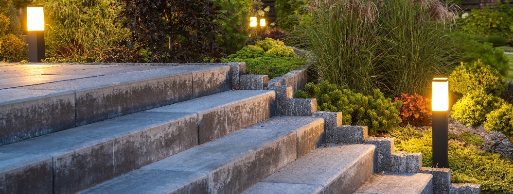 Gepflegter Garten mit Betontreppe und dekorativer Beleuchtung